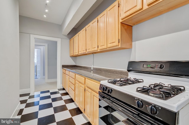 3024 Tilden St NW # 6, Washington, DC 20008 - kitchen with range with gas stovetop, light brown cabinetry, dark flooring, baseboards, and dark countertops