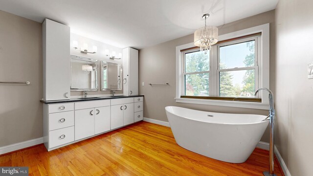 225 Dupont Cir, Wilmington, DE 19809 - full bathroom with double vanity, a freestanding tub, wood finished floors, and a chandelier