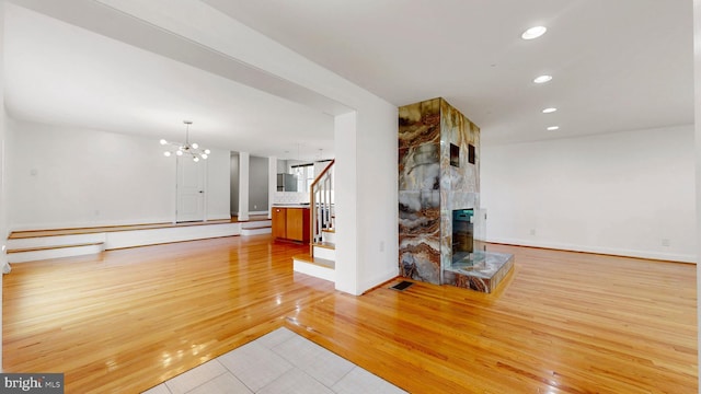 225 Dupont Cir, Wilmington, DE 19809 - unfurnished living room with recessed lighting, light wood-style floors, a fireplace, stairway, and a chandelier