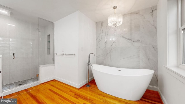 225 Dupont Cir, Wilmington, DE 19809 - full bathroom featuring a soaking tub, a stall shower, wood finished floors, and a chandelier