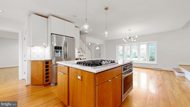 225 Dupont Cir, Wilmington, DE 19809 - kitchen with stainless steel appliances, light wood-style flooring, white cabinets, and hanging light fixtures