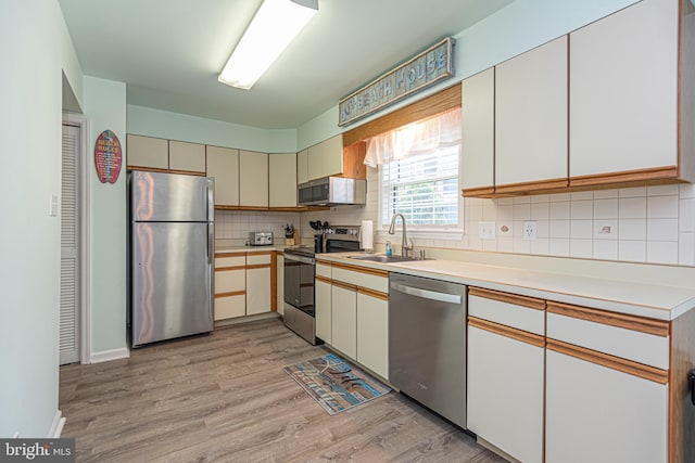 104 120th St Unit D82, Ocean City, MD 21842 - kitchen with stainless steel appliances, a sink, light wood-type flooring, backsplash, and light countertops