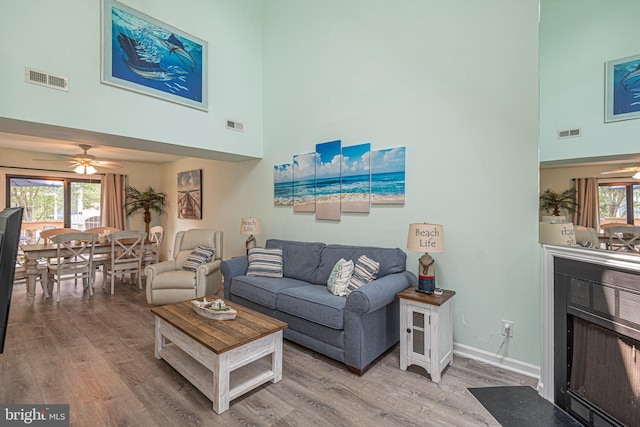 104 120th St Unit D82, Ocean City, MD 21842 - living room with a towering ceiling, wood finished floors, a fireplace with flush hearth, ceiling fan, and baseboards