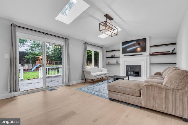 1606 Montmorency Dr, Vienna, VA 22182 - living room featuring a skylight, vaulted ceiling, wood finished floors, a glass covered fireplace, and plenty of natural light