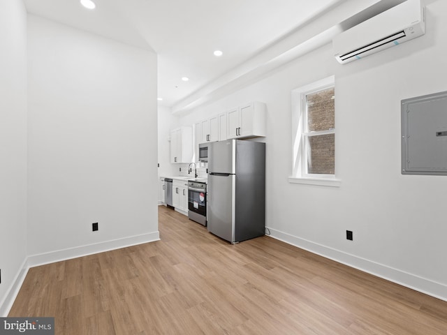 2331 N Front St, Philadelphia, PA 19133 - kitchen featuring appliances with stainless steel finishes, electric panel, an AC wall unit, light wood-type flooring, and white cabinets