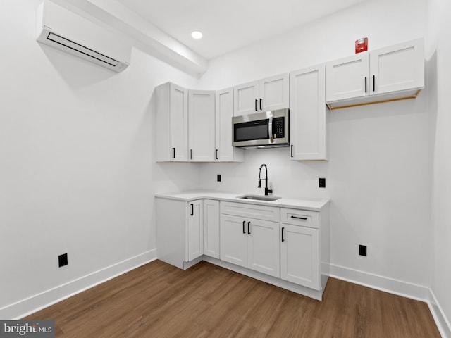 2331 N Front St, Philadelphia, PA 19133 - kitchen featuring stainless steel microwave, a sink, an AC wall unit, wood finished floors, and recessed lighting
