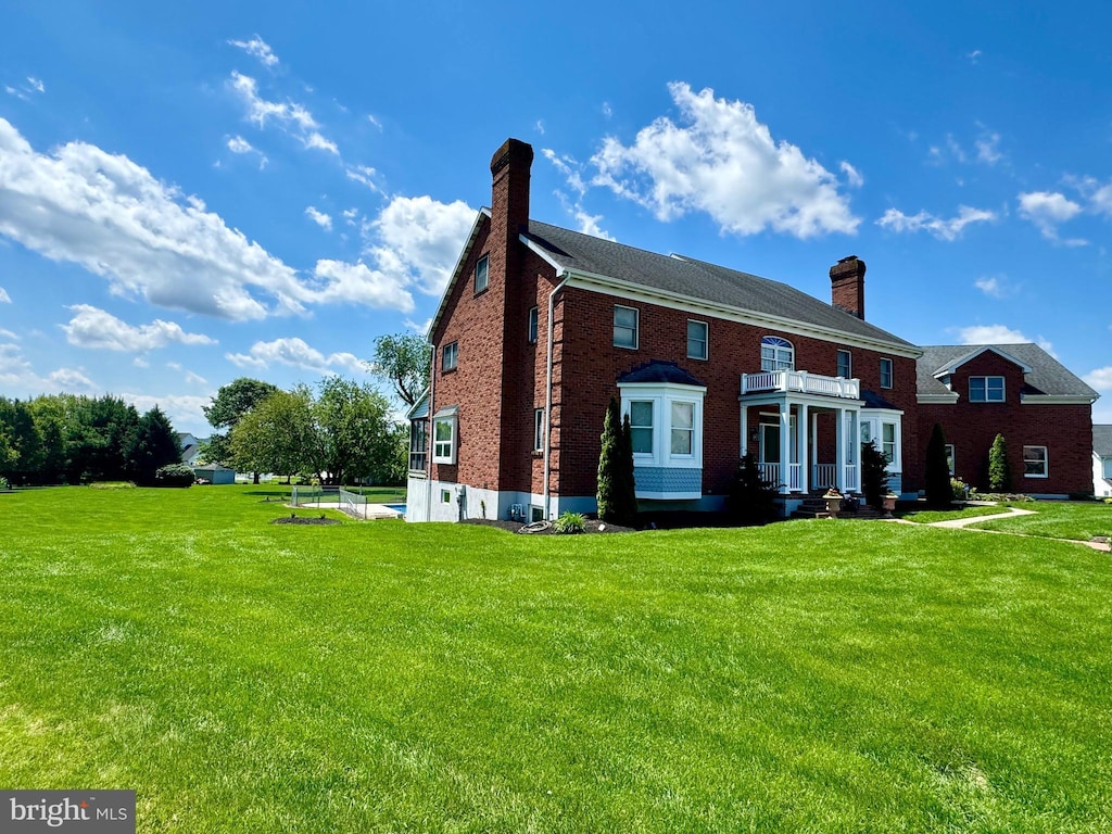 324 W Orchard Dr, Palmyra, PA 17078 - view of front facade with a chimney, a front yard, brick siding, and a balcony