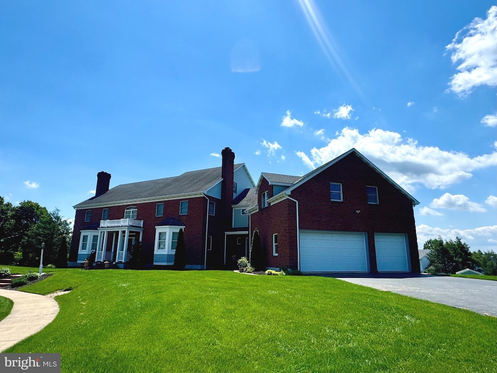 324 W Orchard Dr, Palmyra, PA 17078 - view of front of property featuring a garage, a front yard, brick siding, asphalt driveway, and a chimney