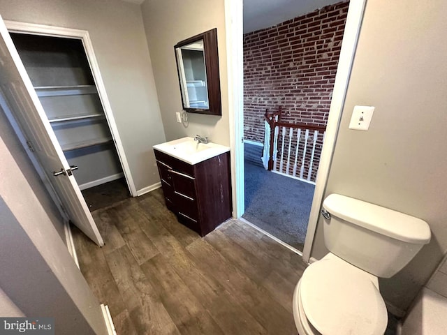 233 S Gilmor St, Baltimore, MD 21223 - bathroom with vanity, wood finished floors, toilet, and brick wall