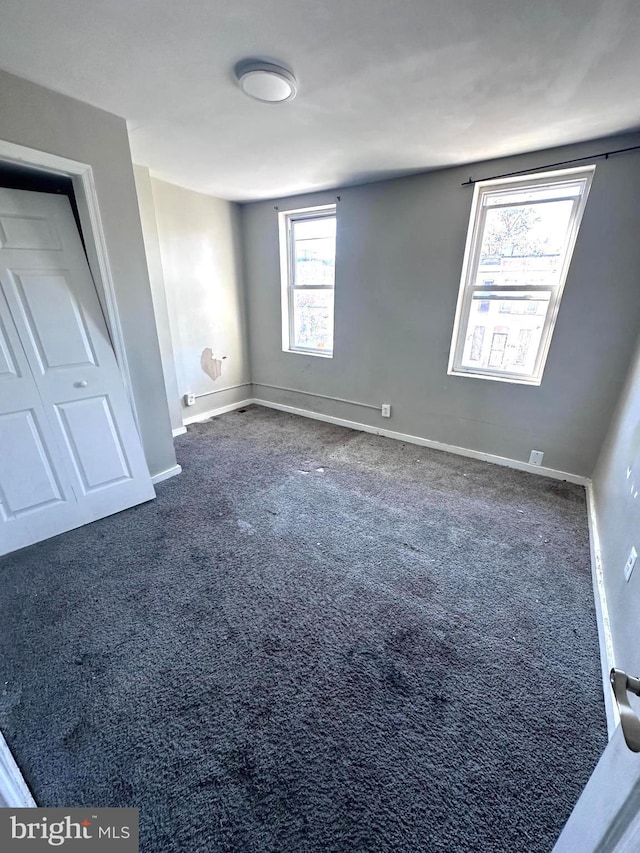 233 S Gilmor St, Baltimore, MD 21223 - unfurnished bedroom with multiple windows, dark carpet, and baseboards