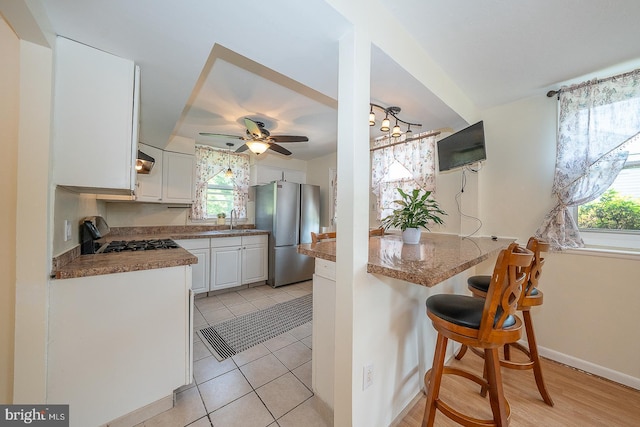 405 Garden Ln, Aston, PA 19014 - kitchen featuring freestanding refrigerator, a sink, a ceiling fan, a kitchen bar, and white cabinetry