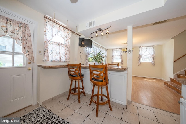 405 Garden Ln, Aston, PA 19014 - kitchen featuring light tile patterned floors, a breakfast bar, white cabinets, and baseboards