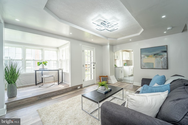 3232 N Rolling Rd, Baltimore, MD 21244 - living area featuring a tray ceiling, arched walkways, wood finished floors, and a textured ceiling
