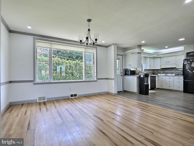 1927 N 15th St, Reading, PA 19604 - kitchen with black appliances, a chandelier, crown molding, wood finished floors, and baseboards