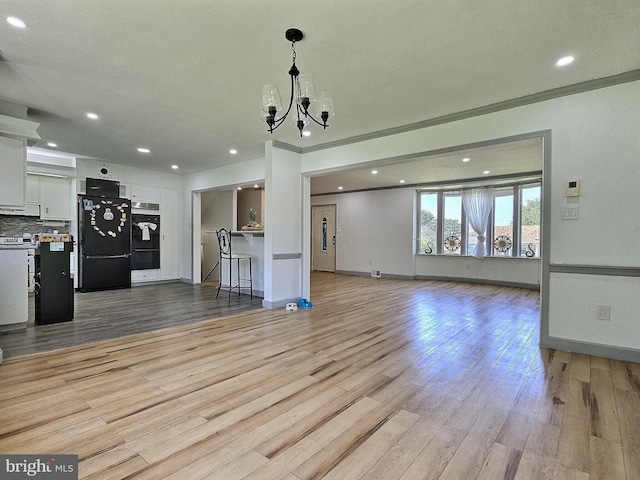 1927 N 15th St, Reading, PA 19604 - unfurnished living room with a chandelier, light wood finished floors, recessed lighting, baseboards, and ornamental molding