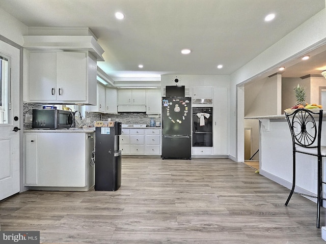 1927 N 15th St, Reading, PA 19604 - kitchen with black appliances, exhaust hood, recessed lighting, decorative backsplash, and light wood-style flooring