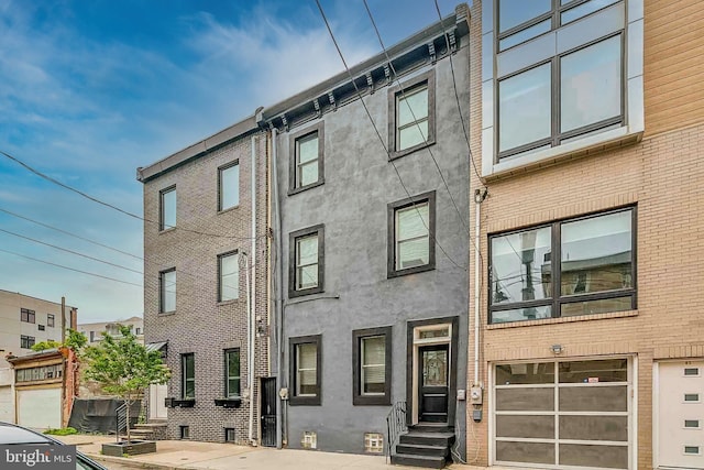 1129 Leopard St, Philadelphia, PA 19123 - view of property with entry steps, stucco siding, and an attached garage