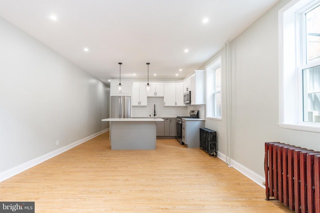 2112 Pine St Unit 2, Philadelphia, PA 19103 - kitchen with radiator heating unit, stainless steel appliances, a center island, a sink, and light wood-style flooring