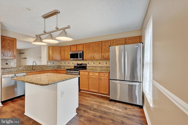6119 Starburn Path, Columbia, MD 21045 - kitchen with stainless steel appliances, backsplash, a kitchen island, decorative light fixtures, and wood finished floors