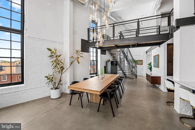 1220 Bank St Unit 304, Baltimore, MD 21202 - dining room featuring a high ceiling, brick wall, finished concrete floors, stairs, and a chandelier