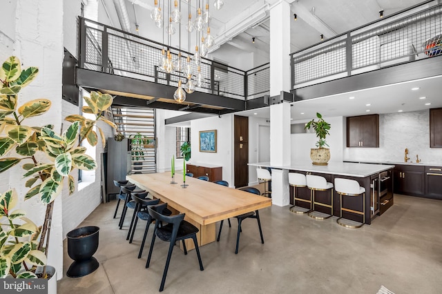 1220 Bank St Unit 304, Baltimore, MD 21202 - dining area with finished concrete floors, stairway, a high ceiling, and a chandelier