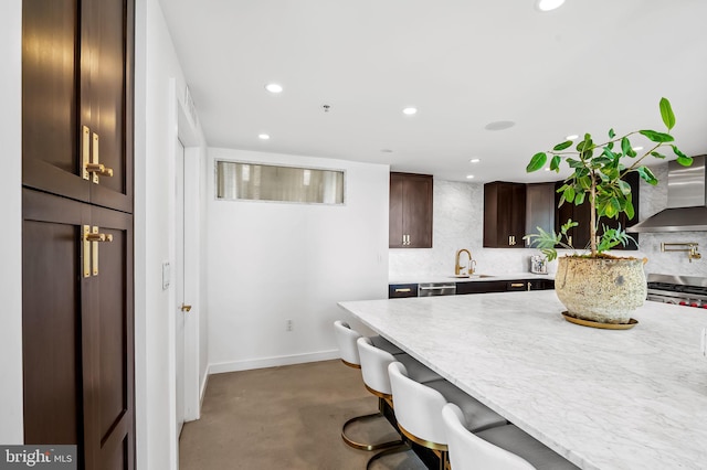 1220 Bank St Unit 304, Baltimore, MD 21202 - kitchen with wall chimney range hood, a kitchen bar, concrete floors, dark brown cabinetry, and a sink