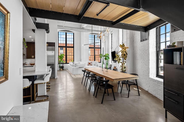 1220 Bank St Unit 304, Baltimore, MD 21202 - dining room featuring finished concrete flooring, brick wall, a chandelier, and a high ceiling