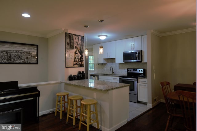 6403 Limerick Ct, Springfield, VA 22152 - kitchen featuring appliances with stainless steel finishes, dark wood-style floors, a kitchen bar, ornamental molding, and white cabinets