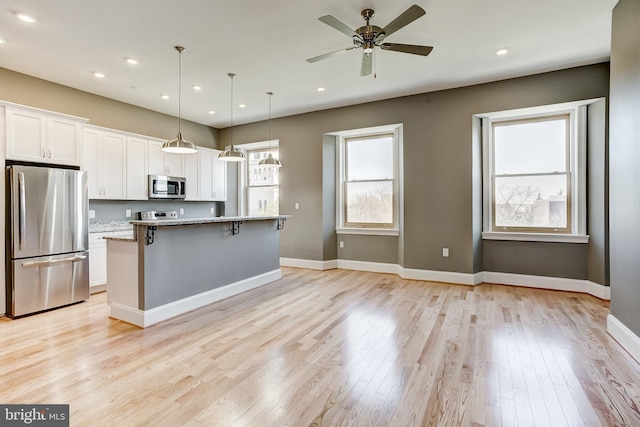 1214 Eutaw Pl, Baltimore, MD 21217 - kitchen with appliances with stainless steel finishes, white cabinets, a kitchen breakfast bar, light wood-type flooring, and a center island