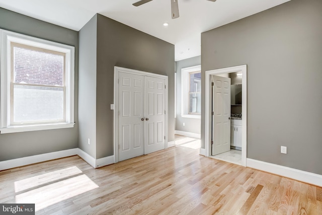 1214 Eutaw Pl, Baltimore, MD 21217 - unfurnished bedroom featuring a closet, baseboards, multiple windows, and light wood-style floors
