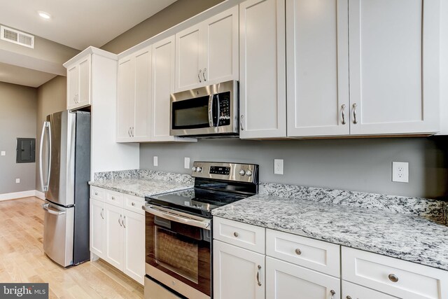 1214 Eutaw Pl, Baltimore, MD 21217 - kitchen featuring appliances with stainless steel finishes, white cabinets, light wood-style floors, light stone countertops, and baseboards