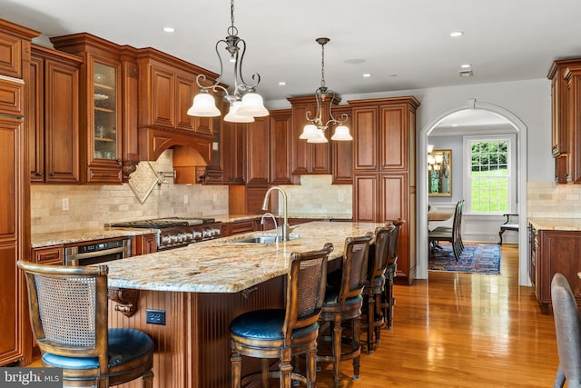 5835 Ridgeview Dr, Doylestown, PA 18902 - kitchen featuring a sink, wood finished floors, light stone countertops, arched walkways, and recessed lighting