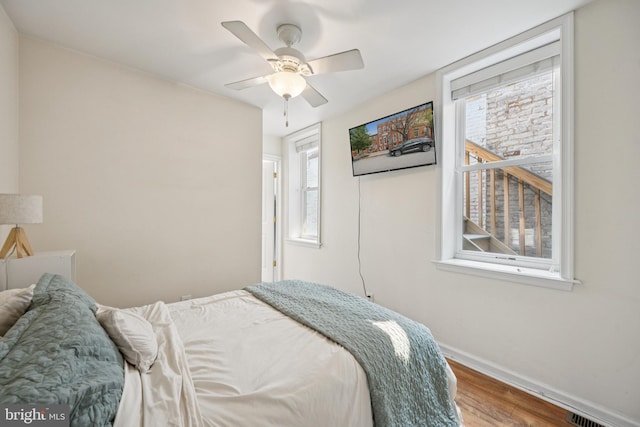 3032 Dillon St, Baltimore, MD 21224 - bedroom with baseboards, wood finished floors, multiple windows, and ceiling fan