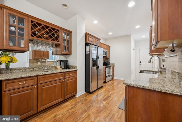 3032 Dillon St, Baltimore, MD 21224 - kitchen with stainless steel appliances, a sink, backsplash, light wood finished floors, and light stone counters