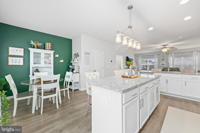 492 Parkland Dr, Stephenson, VA 22656 - kitchen with a kitchen island, white cabinets, light wood-style floors, a sink, and a ceiling fan
