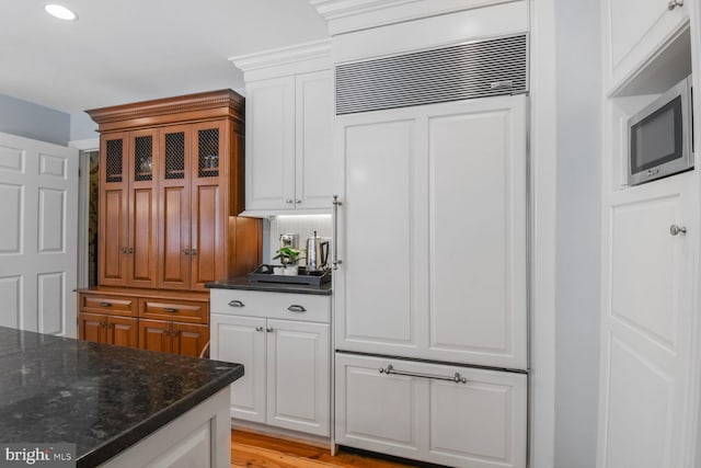 11801 Glen Mill Rd, Potomac, MD 20854 - kitchen featuring paneled built in refrigerator, stainless steel microwave, white cabinetry, and dark stone counters