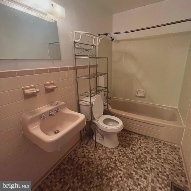 110 S Broadway, Frostburg, MD 21532 - bathroom featuring shower / washtub combination, toilet, a wainscoted wall, a sink, and tile walls
