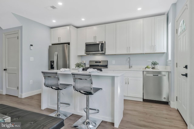 1515 Montana Ave NE, Washington, DC 20018 - kitchen featuring stainless steel appliances, a kitchen island, a sink, light wood finished floors, and white cabinetry