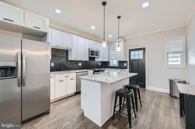 3540 Keswick Rd, Baltimore, MD 21211 - kitchen featuring appliances with stainless steel finishes, crown molding, decorative backsplash, a kitchen island, and wood finished floors