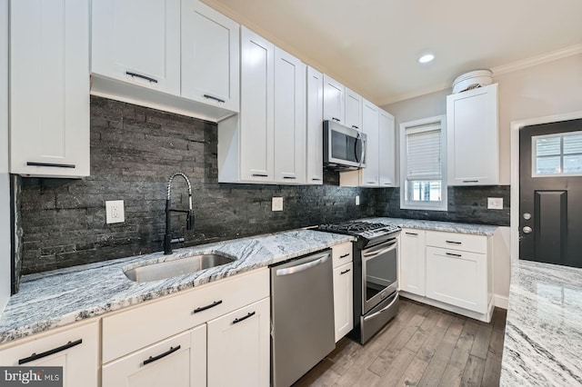3540 Keswick Rd, Baltimore, MD 21211 - kitchen featuring appliances with stainless steel finishes, a sink, ornamental molding, tasteful backsplash, and wood finished floors
