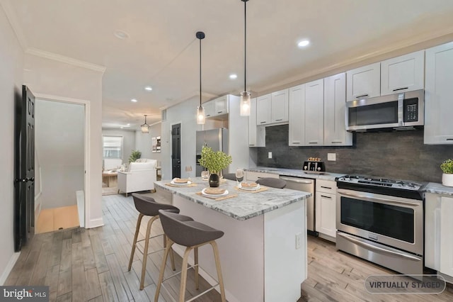 3540 Keswick Rd, Baltimore, MD 21211 - kitchen featuring stainless steel appliances, ornamental molding, a center island, light wood-type flooring, and a breakfast bar area