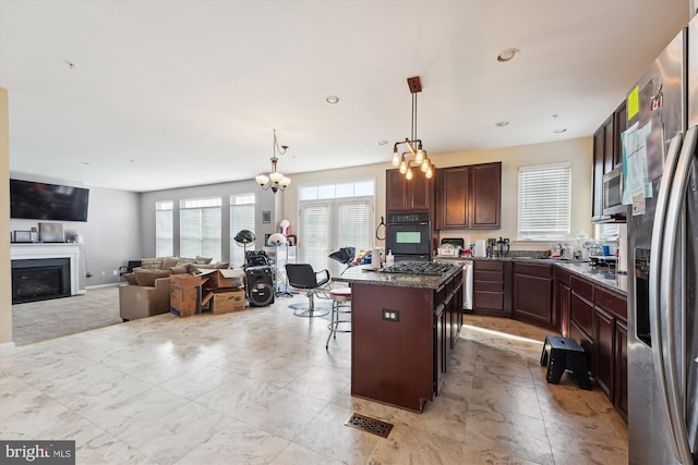 7306 Sudley Ave, Brandywine, MD 20613 - kitchen with appliances with stainless steel finishes, a breakfast bar area, a glass covered fireplace, an island with sink, and pendant lighting