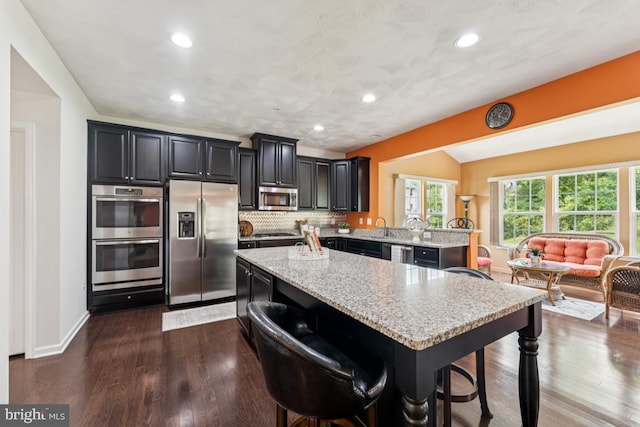 14302 Hidden Forest Dr, Accokeek, MD 20607 - kitchen featuring appliances with stainless steel finishes, a kitchen island, a breakfast bar area, light stone countertops, and recessed lighting