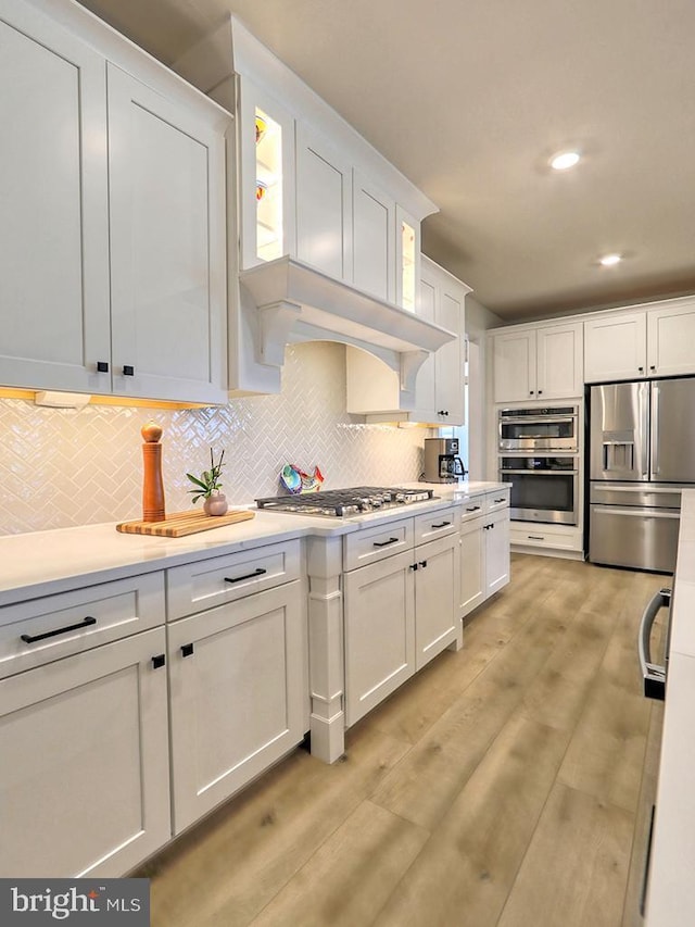 33016 Ethan Allen Dr, Rehoboth Beach, DE 19971 - kitchen featuring appliances with stainless steel finishes, white cabinetry, light countertops, tasteful backsplash, and recessed lighting