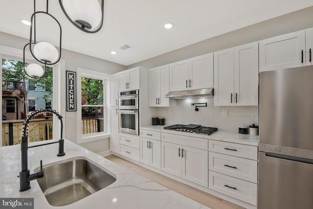 1713 4th St NW, Washington, DC 20001 - kitchen featuring stainless steel appliances, a sink, under cabinet range hood, white cabinetry, and light stone countertops