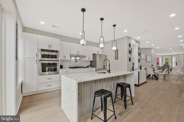 1713 4th St NW, Washington, DC 20001 - kitchen with a sink, light wood-type flooring, under cabinet range hood, white cabinetry, and appliances with stainless steel finishes