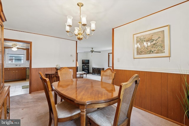 909 Rocklynn Rd, Springfield, PA 19064 - dining area with a ceiling fan, a chandelier, wainscoting, wooden walls, and light colored carpet