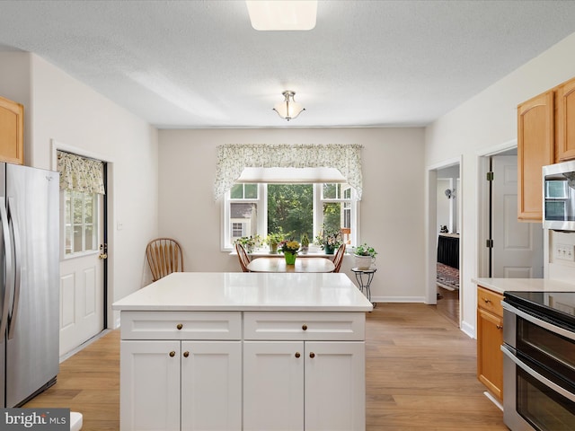 2 Assawoman Ave, Ocean View, DE 19970 - kitchen featuring stainless steel appliances, light wood-type flooring, light countertops, a textured ceiling, and white cabinetry
