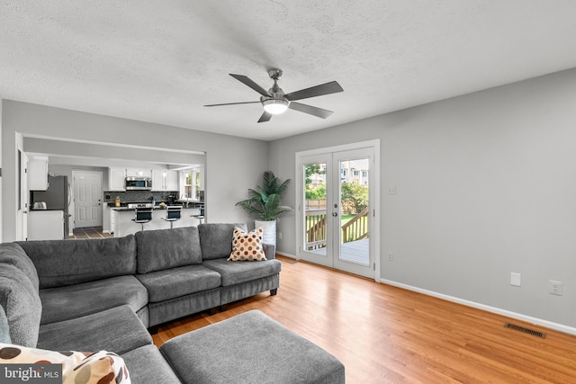 12407 Rousseau Ter, North Potomac, MD 20878 - living room with light wood-type flooring, a ceiling fan, and a textured ceiling