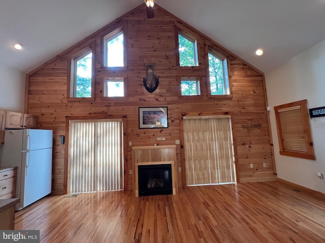 1000 Cardinal View Rd, Paw Paw, WV 25434 - unfurnished living room featuring high vaulted ceiling, light wood-type flooring, wood walls, and a tile fireplace